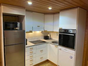 萨利色尔卡Panoraama 2的厨房配有白色橱柜和不锈钢冰箱