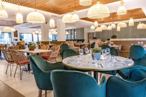 勒卡斯特雷特格兰德普利克斯餐厅酒店的餐厅设有桌椅和吊灯。