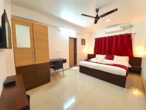 班加罗尔Sai Shreyas Residency, Best Hotel near Bangalore Airport的一间卧室配有一张带红色窗帘的床和一张书桌