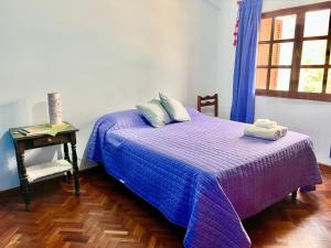 圣萨尔瓦多德朱Tu lugar La Viña的一间卧室配有一张紫色床、一张桌子和一扇窗户