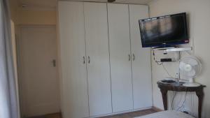 约翰内斯堡玛格丽特广场酒店的一间带电视和白色橱柜的客厅