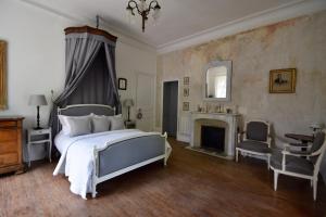 BenonManoir de Plaisance的一间卧室配有一张床、一个壁炉和一把椅子
