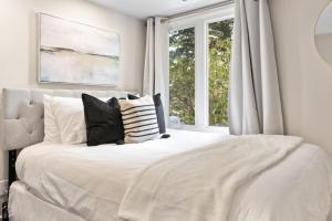 蓝山Blue Mountain Chalet Condo with Amazing Location的卧室配有带枕头的白色床和窗户。