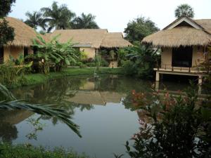 巴吞他尼荫娜特度假酒店的前面有池塘的房子