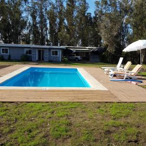 米纳斯Piedra De Agua Chacra, casa, piscina, bosque, río.的一个带甲板、两把椅子和遮阳伞的游泳池
