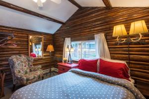 派恩代尔小木屋汽车旅馆的一间卧室设有木墙和一张带红色枕头的床。