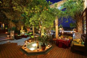 非斯里亚德蔓藤酒店及Spa的户外庭院设有热水浴池,配有树木和桌子