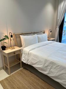马斯喀特The Beach House的卧室配有白色的床和植物桌子