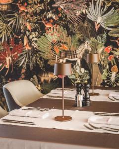 波德戈里察SIGNUM Hotel的一张桌子,上面有两盏灯和花卉墙