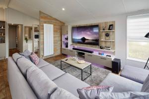 滨海纽比金Sandy Bay Lodge的带沙发和大屏幕电视的客厅