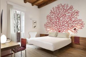 卡利亚里Casa Clat的卧室配有白色的床,墙上挂着一棵大树