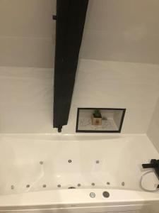 普瓦捷Cosy & Tendance Spa的白色浴缸上方墙上的照片