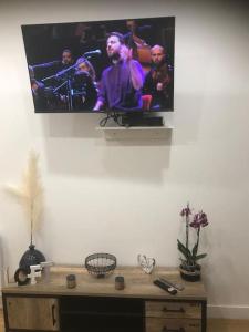 普瓦捷Cosy & Tendance Spa的挂在墙上的电视,上面有乐队