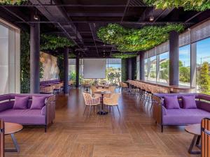 玛琅Grand Mercure Malang的餐厅设有紫色的长沙发和桌子及窗户