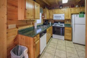 鸽子谷ER206 - Mountain Rendezvous Great location - Close to town! cabin的厨房配有木制橱柜和白色冰箱。