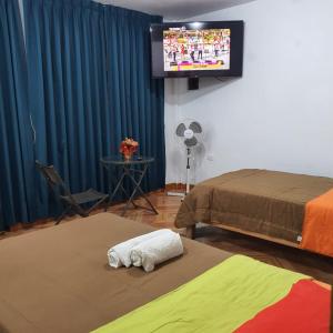 利马Lima Airport Hostel with FREE AIRPORT PICK UP的客房设有两张床和一台平面电视。