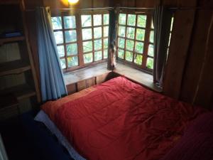 内尔图梅Cabañas Llakolen的一间设有红色床的卧室,位于带窗户的房间内