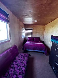 延基韦Lugar de descanso, con Tinaja al aire libre.的小房间设有紫色的床和窗户
