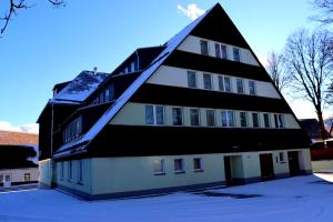 奥泊维森塔尔Schwarzes Ross Hotel & Restaurant Oberwiesenthal的一座黑色和白色的建筑,地面上积雪
