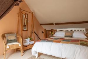 卡伦普顿Highdown Farm Holiday Cottages的一间卧室配有一张大床和一把椅子