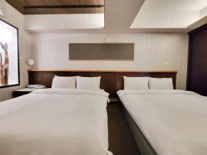 台中市雀客快捷台中逢甲的配有白色床单的酒店客房内的两张床