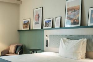 维尔Hotel Münchwilen的酒店客房设有一张床,墙上挂着一些图片