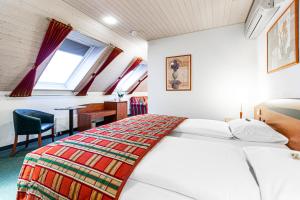 维尔Hotel Münchwilen的一间卧室配有一张床、一张书桌和一个窗户。