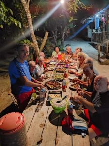 Pulau MansuarMambetron Homestay Raja Ampat的一群人坐在木桌旁吃食物