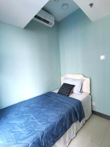 LontarBenson Tower Surabaya Apartment 2BR by Le Ciel Hospitality的一间卧室配有一张蓝色墙壁的床