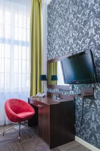 格但斯克Hotel Artus - Old Town的客房设有书桌、电视和红色椅子