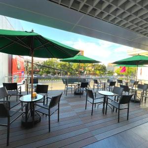 雅加达Grand G7 Hotel Pasar baru的一个带桌椅和绿色遮阳伞的庭院