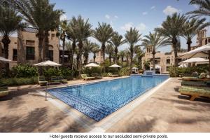 迪拜Jumeirah Dar Al Masyaf的棕榈树和遮阳伞度假村的游泳池