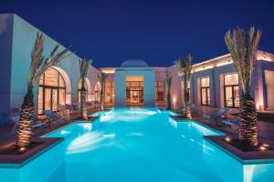 哈马马特巴迪拉成人酒店的一座棕榈树游泳池,晚上在房子里