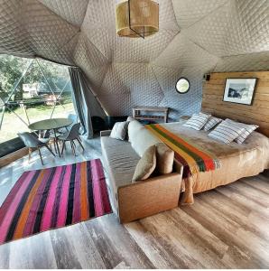 特拉福镇Glamping Vulcanche的帐篷内的卧室,配有一张床和一张桌子