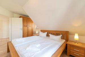 KarninFerienhaus Karnin A的卧室配有一张带白色床单和枕头的大床。