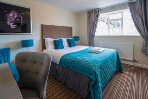克鲁白狮酒店的一间卧室配有一张带蓝色毯子和椅子的床