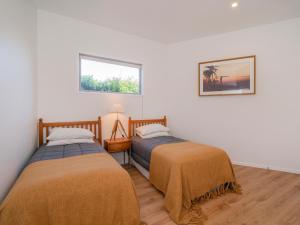 旺阿马塔Coast Awhile - Whangamata Holiday Home的配有2张床的白色墙壁和窗户。