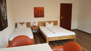开姆尼茨凤凰旅馆的一间设有两张床、椅子和门的房间