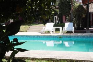 塔巴贝拉Hotel Venus de Valdivia Aeropuerto的两把白色椅子坐在游泳池旁