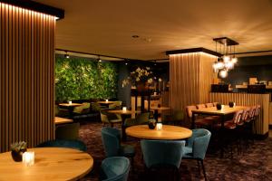乌登阿劳斯酒店的餐厅设有木桌和椅子,种有植物