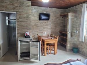 坎布里Pousada Mar & Sol de Camburi的砖墙上的带桌子和电视的用餐室