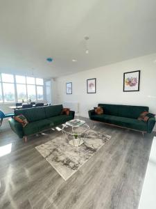 弗特威克Flitwick Luxury 3 Bedroom Apartment的客厅配有两张绿色沙发和一张桌子