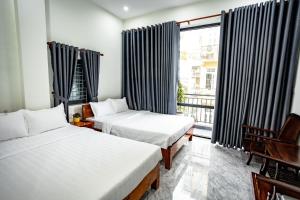 顺化Mini hotel Lạc Hồng的酒店客房设有两张床和窗户。