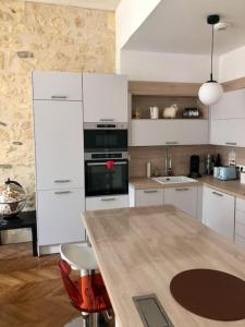 波尔多Fantastic 3-Room apartment heart of les Chartrons - Bordeaux的厨房配有白色橱柜、桌子和炉灶。