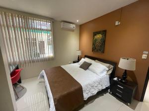 PorteteLOFTSCACAO APARTMENTS, Villas Cacao, near to Playa Bonita Limón的一间卧室配有一张床和一张红色椅子