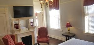 查塔努加The Mayor's Mansion Inn的一间卧室设有壁炉、椅子和电视。