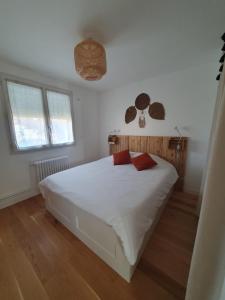 勒芒Maison Zen proche circuit的卧室配有白色床和2个红色枕头