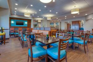 盖恩斯维尔Drury Inn & Suites Gainesville的餐厅设有木桌和蓝色椅子