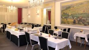 昂热法兰西酒店的一间用餐室,配有白色的桌椅和绘画作品