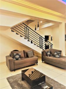 阿布贾Entire Serviced Two bedroom duplex Abuja - 24hr WIFI, POWER, OFFICE, FULL KITCHEN的客厅设有两张沙发和一个楼梯